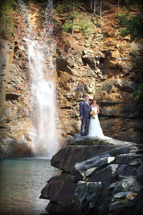 A wedding couple stands in front of the waterfall at the quarry at Carrigan Farms in Mooresville, NC.